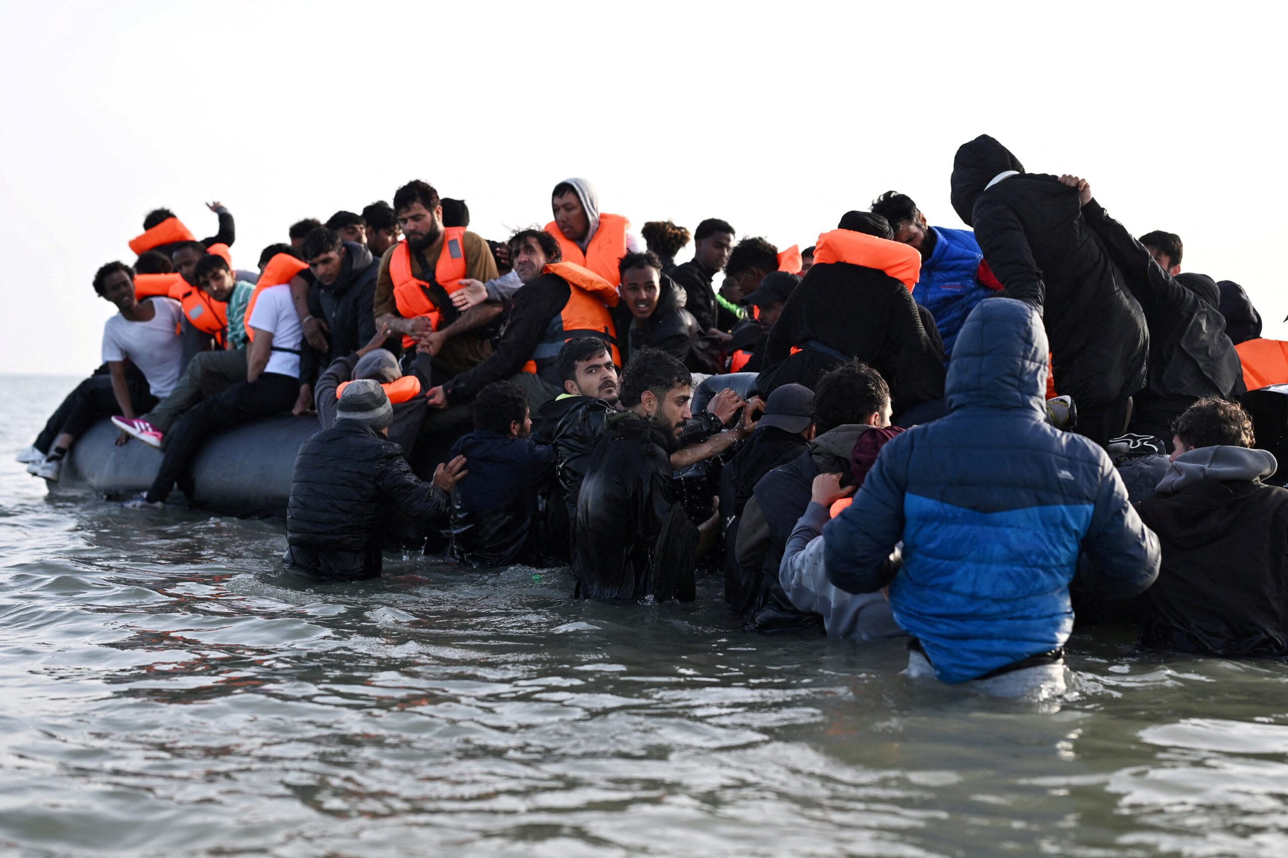 A group of migrants board an inflatable dinghy before leaving the coast of northern France, in Gravelines