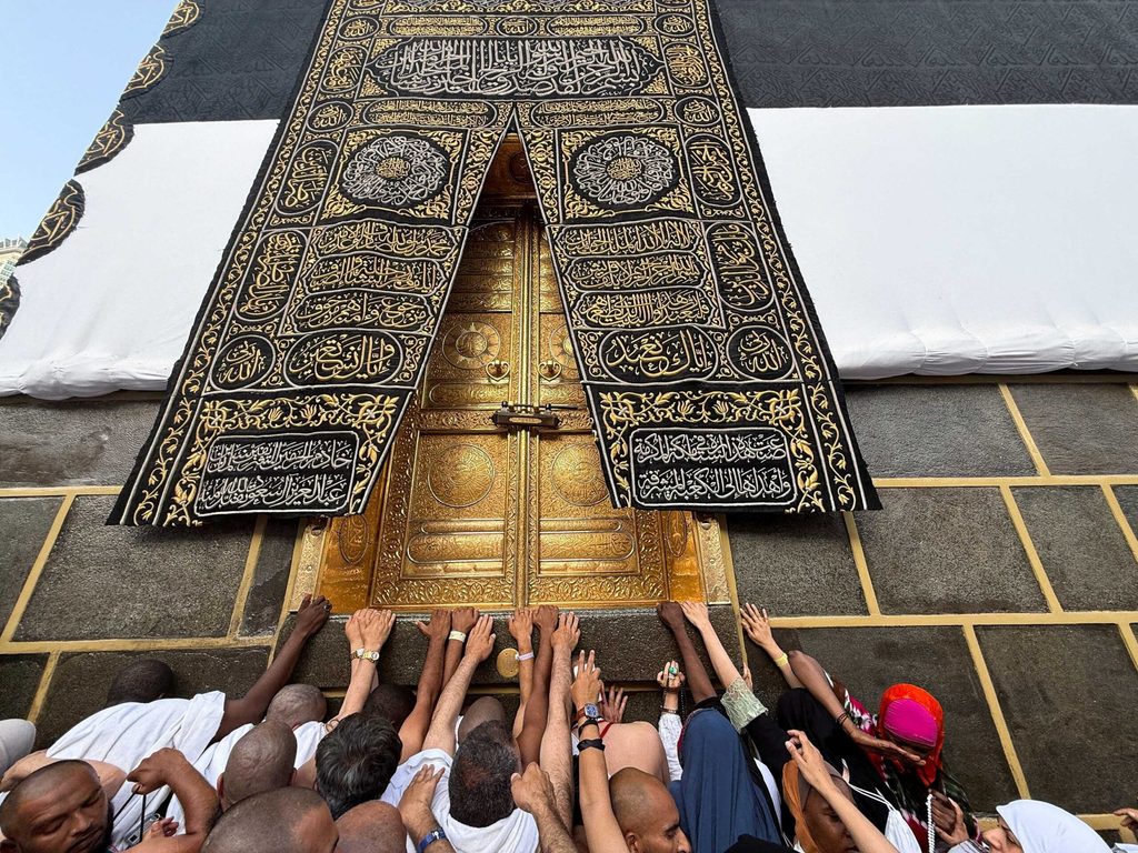 Muslim pilgrims reach out to touch the Kaaba's door at the Grand Mosque, ahead of the annual hajj pilgrimage, in Mecca