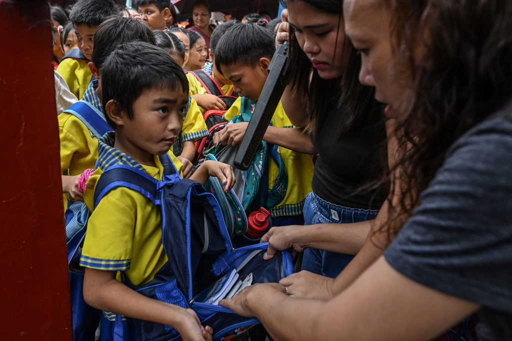 Security guard checks students' bags before they enter school