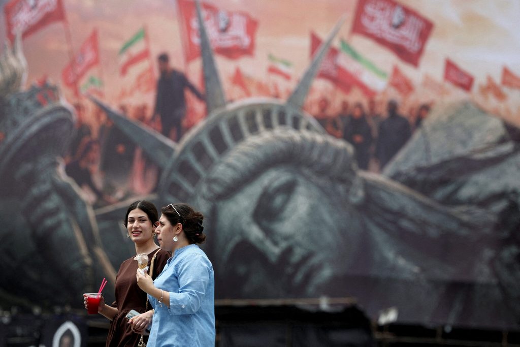 People walk past an anti-U.S. billboard on a street in Tehran