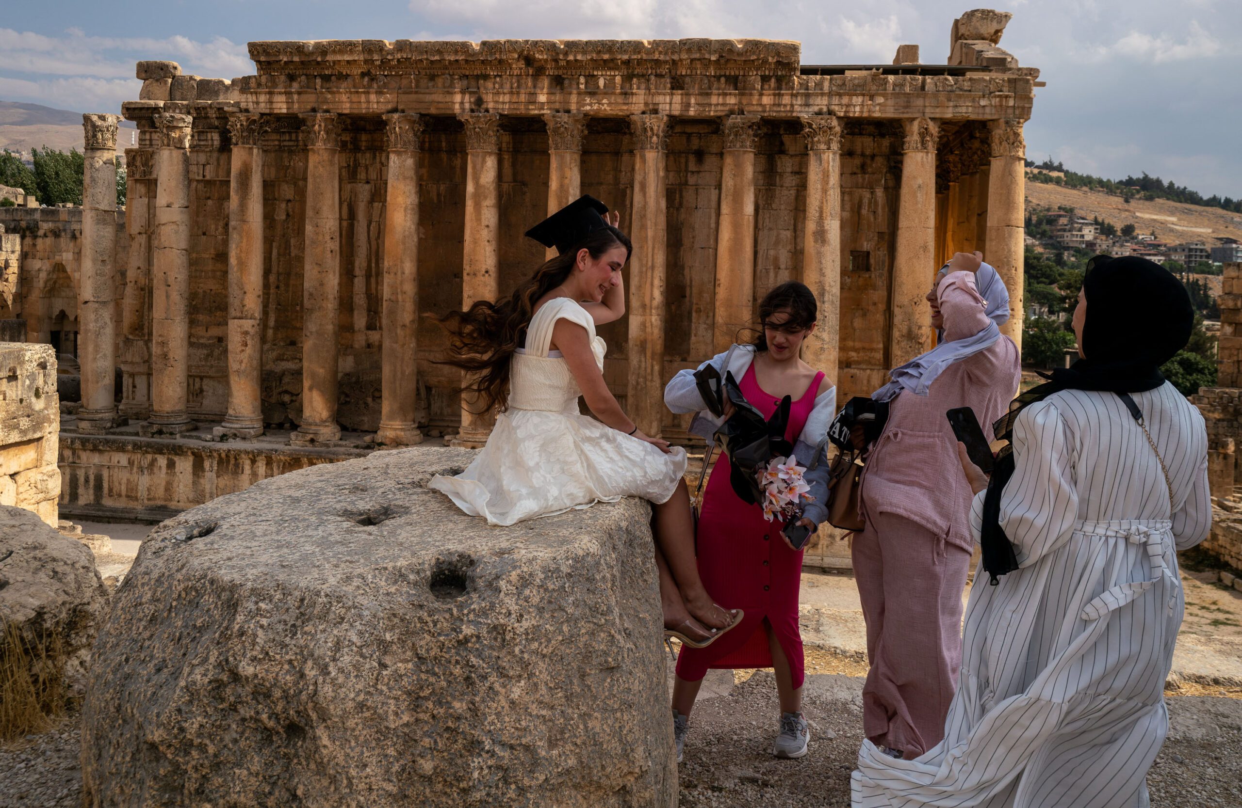 A newly graduated student prepares to pose for a photograph in front of the ruins of the Roman Temple of Bacchus, Baalbek