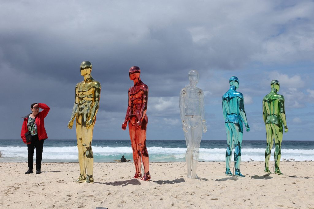 A woman stands next to a sculpture titled ‘ART (Artificial Real Time)’ by artist Erica Zaino on the opening day of the 'Sculpture by the Sea' outdoor exhibition in Bondi