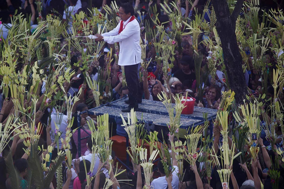 HOLY WATER. A lay minister sprinkles holy water on palm fronds (palaspas) outside St Peter Church along Commonwealth, Quezon City, on Palm Sunday, March 25, 2018. Photo by Darren Langit/Rappler 