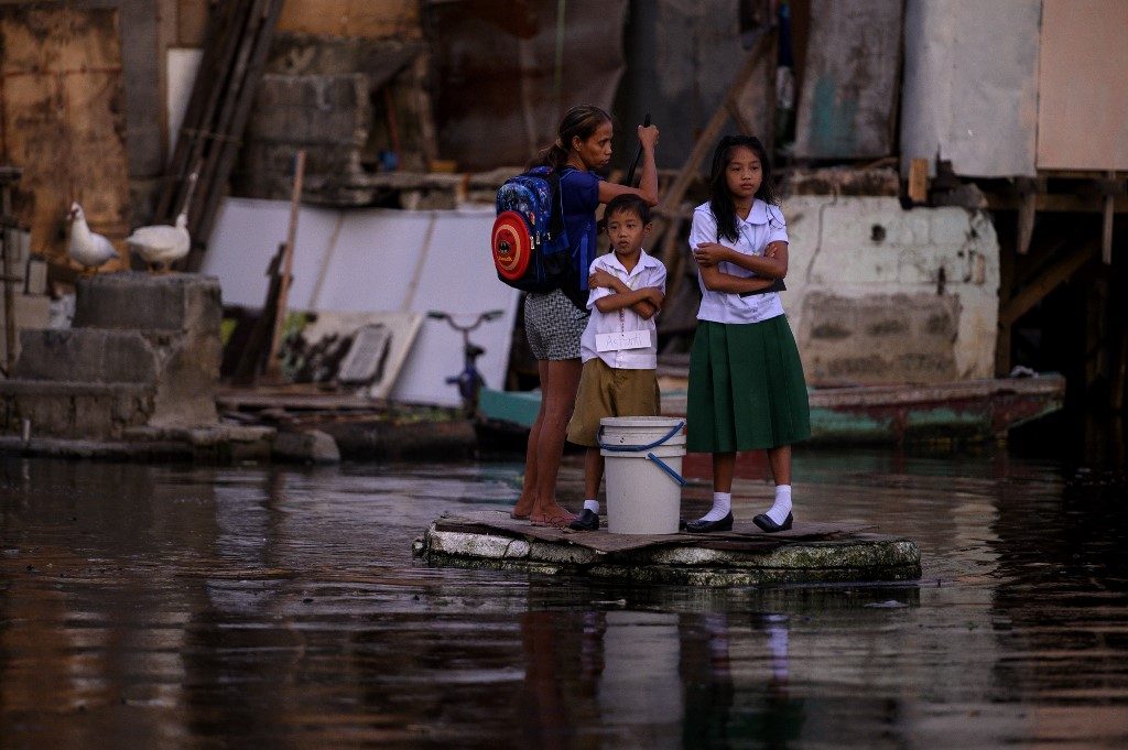 BOAT TO SCHOOL. Panghulo 1 Elementary School students living inside the flooded Artex Compound in Malabon ride on makeshift boats on their way to class. Photo by Noel Celis/AFP 