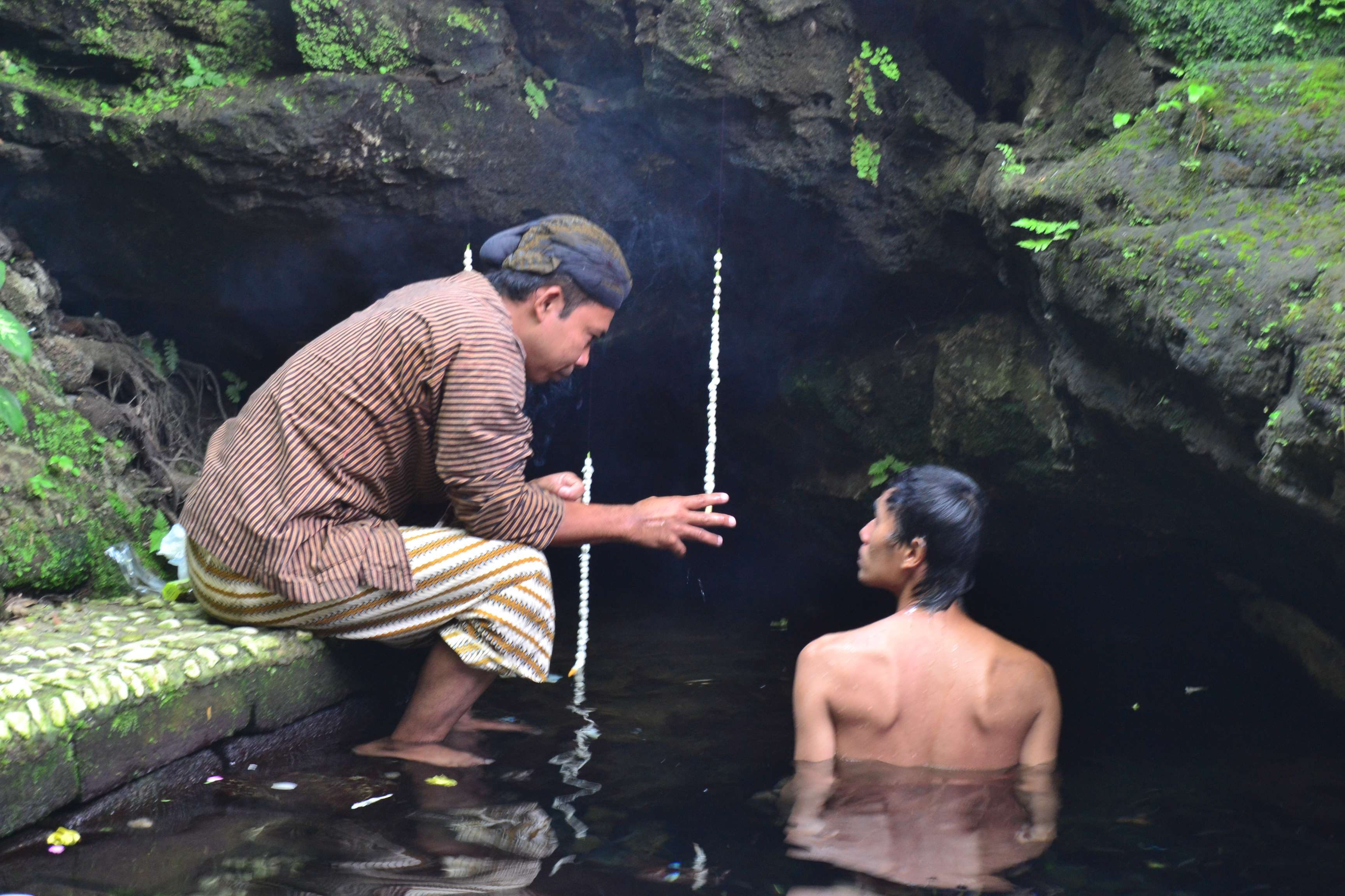 Soleh, juru kunci Sendang Widodaren, mengarahkan pengunjung untuk mandi di depan goa. Foto oleh Dyah Ayu Pitaloka/Rappler 