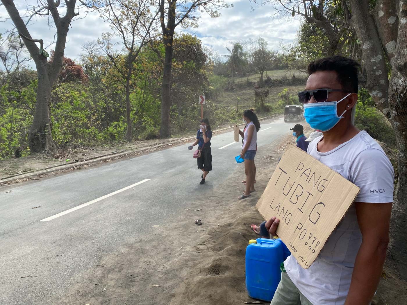 'PANG-TUBIG LANG PO.' Barangay San Guillermo resident Marlon Rosima asks for water from passing vehicles on January 31, 2020. Photo by Mara Cepeda/Rappler 