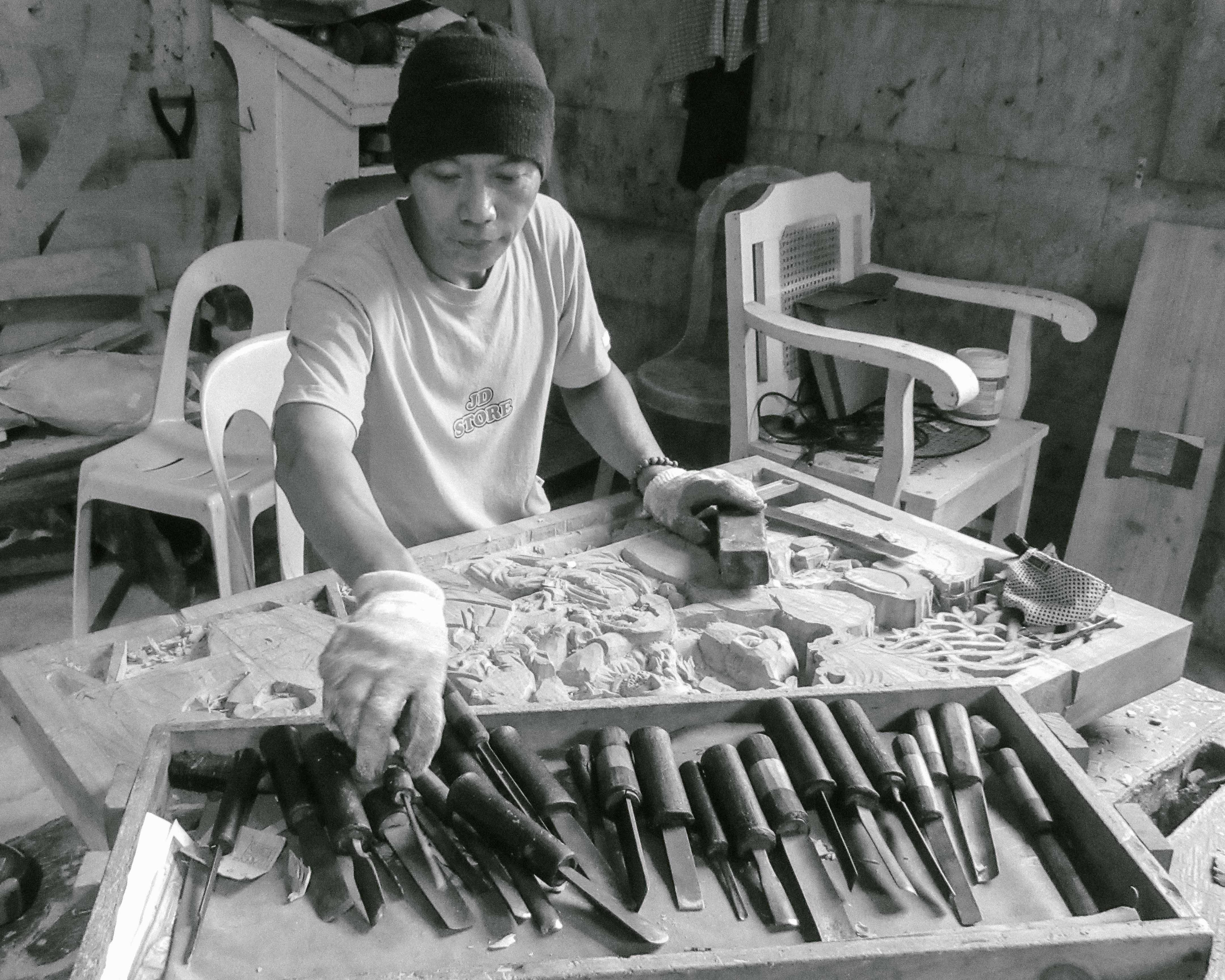 TRADITION. Kuya Arsenio Lagure Jr. is one of the wood carvers preserving tradition, he has passed his craft on to his son. Photo by Josh Berida 