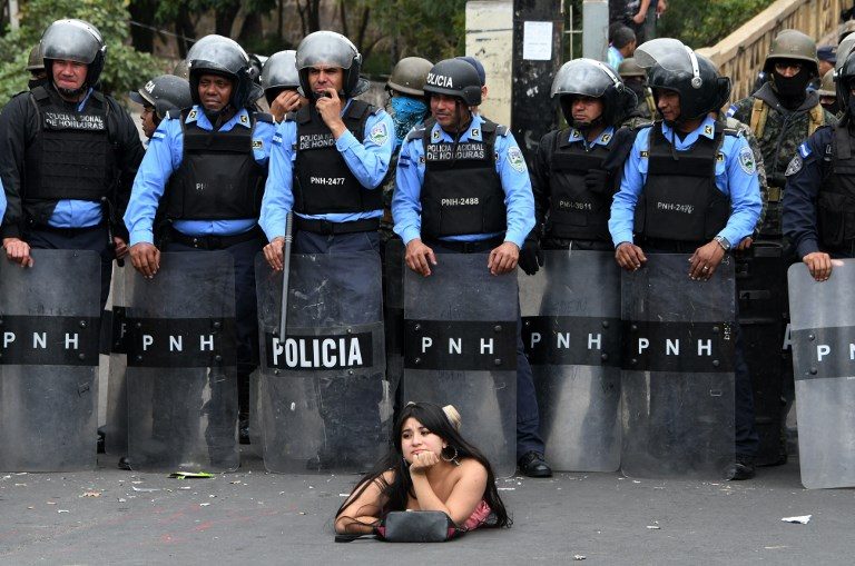 NATIONAL STRIKE. Salvador Nasralla, a supporter of the presidential candidate for the Honduran Opposition Alliance Against the Dictatorship for the past election, lies on the street in front of police officers during a demonstration against the contested re-election of President Juan Orlando Hernandez in Tegucigalpa on January 21, 2018. Photo by Orlando Sierra/AFP 