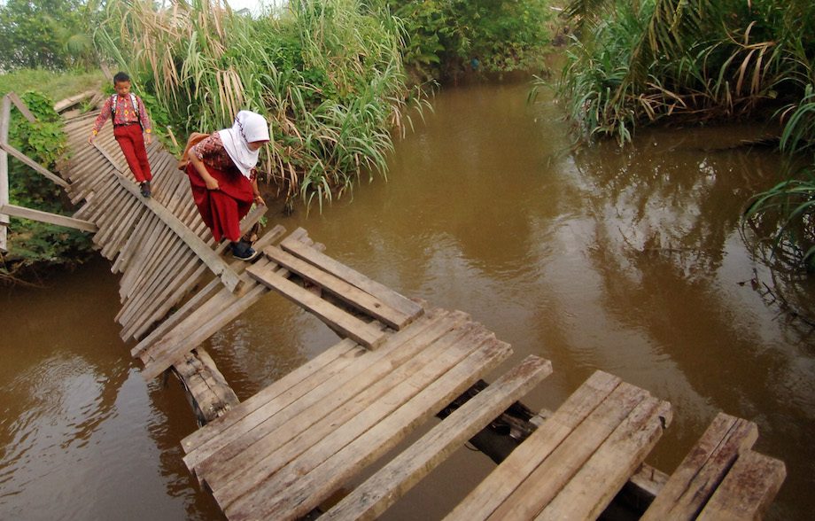 JEMBATAN. Dua murid sekolah dasar berhati-hati melewati jembatan rusak yang menghubungkan kelurahan Kurao Pagang dengan Dadok, di Padang, Sumatera Barat, Kamis (3/12). ANTARA/Iggoy el Fitra 