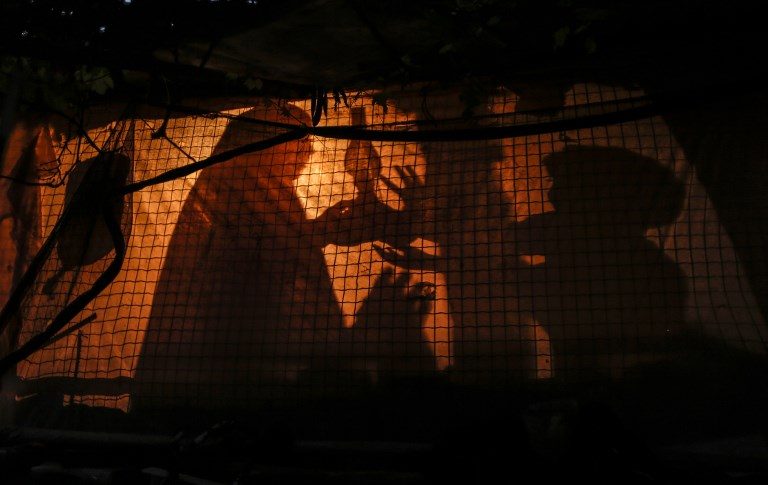 REFUGEES. A Palestinian woman uses a gas lamp during a power cut in an impoverished area of the Khan Younis refugee camp along the Gaza Strip on July 29, 2018. Photo by Mahmud Hams/AFP  
