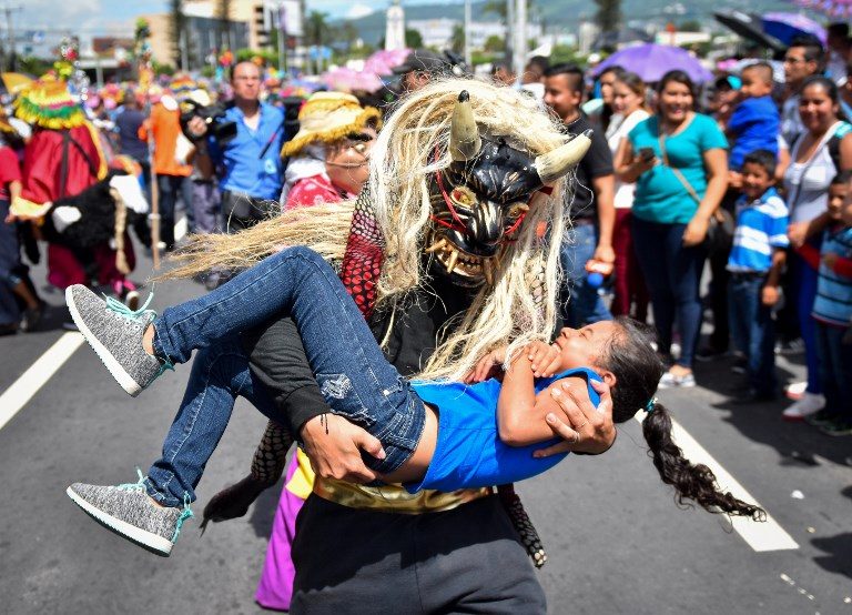 TRADITION. A reveler disguised as a mythological character holds a girl during a parade marking the start of San Salvador's patron saint's festival in honor of Divino Salvador del Mundo (Divine Savior of the World), in San Salvador on August 1, 2018. Photo by Oscar Rivera/AFP  