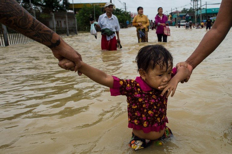 MYANMAR FLOODING. Residents hold onto a child as they walk through floodwaters in the Bago region of Yangon on July 29, 2018. Photo by Ye Aung Thu/AFP  