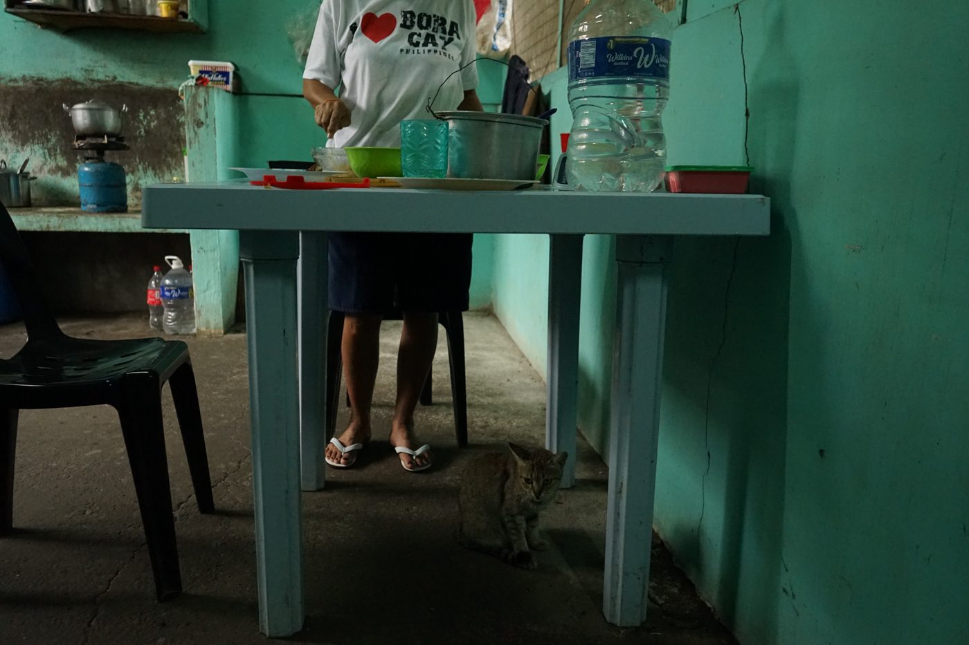  LUNCH TIME. A returnee prepares food for the other women while a stray cat that wandered into the facility sits under the kitchen table.
