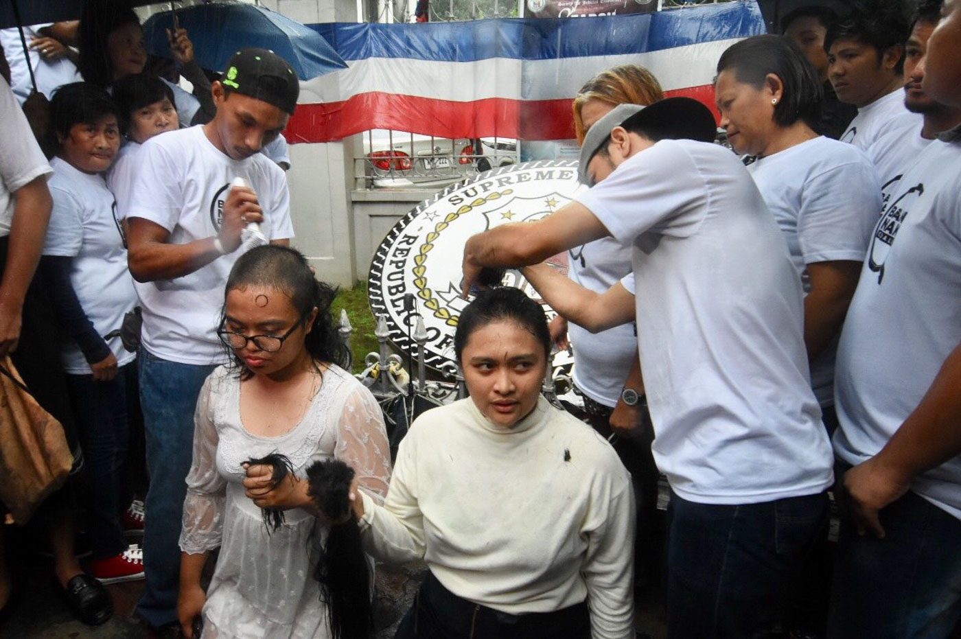 SYMBOLIC HAIRCUT. Members of Bantay Nakaw coalition troop to the Supreme Court amid the rain on June 11, 2018, to shave their heads in protest of the 50% shading threshold applied by the Presidential Electoral Tribunal. Photo by Angie de Silva/Rappler  