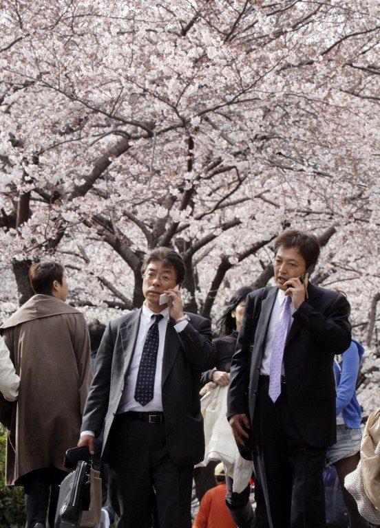UNDER THE CHERRY BLOSSOMS. Japanese businessmen use their mobile phones as they stroll under blooming cherry trees on a riverside promenade in Tokyo on April 1, 2010. Yoshikazu Tsuno/AFP 
