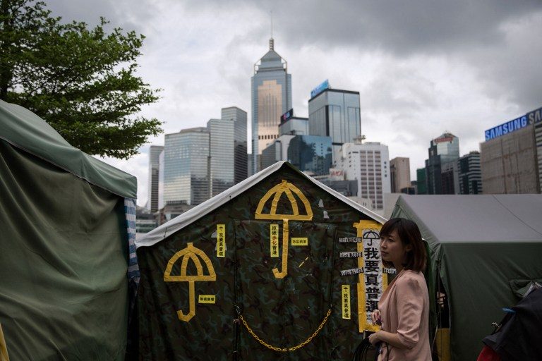 In a picture taken on June 13, 2015, a woman stands in front of yellow umbrellas, a symbol of the pro-democracy movement, stuck on a tent outside the government headquarters in Hong Kong. Dale de la Rey/AFP 