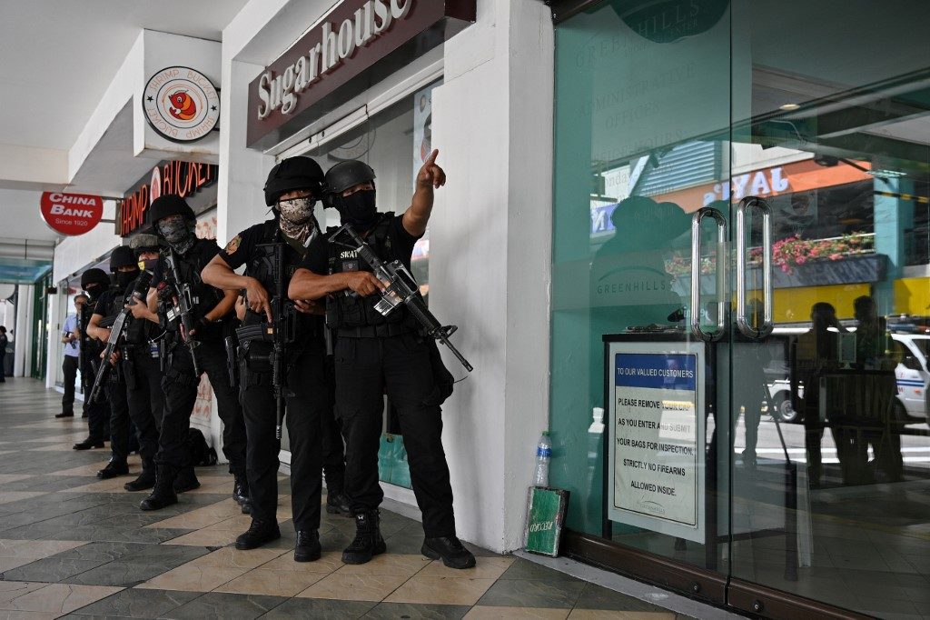 PREPOSITIONED. Members of a police SWAT team take position outside one of the entrances to a mall during the hostage-taking incident. Photo by Ted Aljibe/AFP 