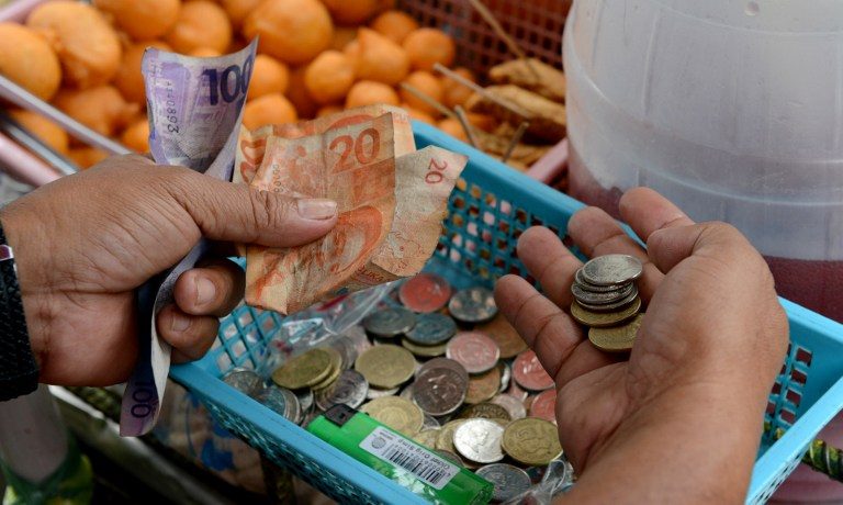 PURCHASING POWER. A street vendor counts Philippine peso currency in Manila on September 13, 2012. File photo by Jay Directo/AFP  