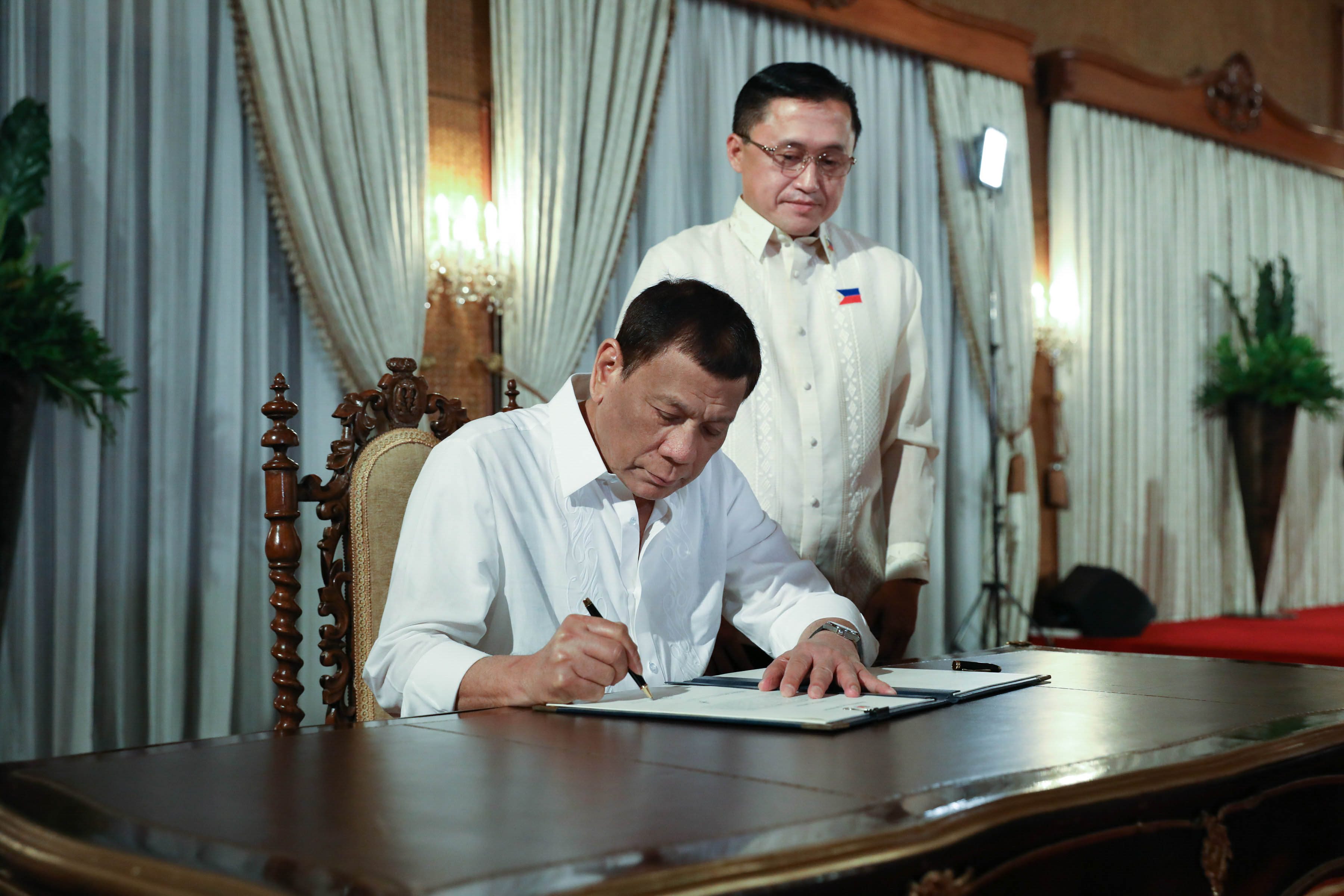 NEW ROLE. President Rodrigo Duterte signs the oath of office of senator-elect Bong Go following his oath-taking ceremony. Malacañang photo  