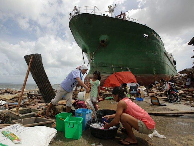 PROTECTION NEEDED. Filipino women wash clothes next to a ship washed ashore, in the super typhoon devastated city of Tacloban, Leyte province, Philippines, 11 November 2013. Photo credit: EPA/FRANCIS R. MALASIG 