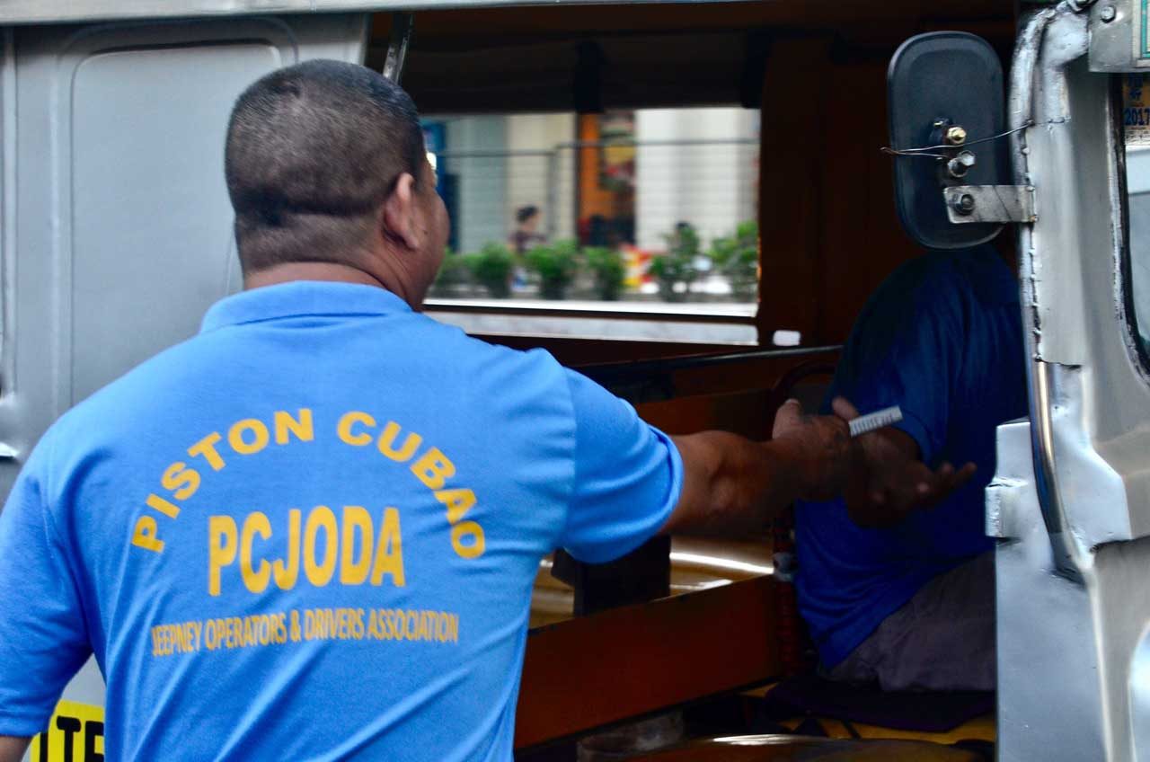 A member of Piston gives handouts to fellow jeepney drivers. Photo by Angie de Silva/Rappler 