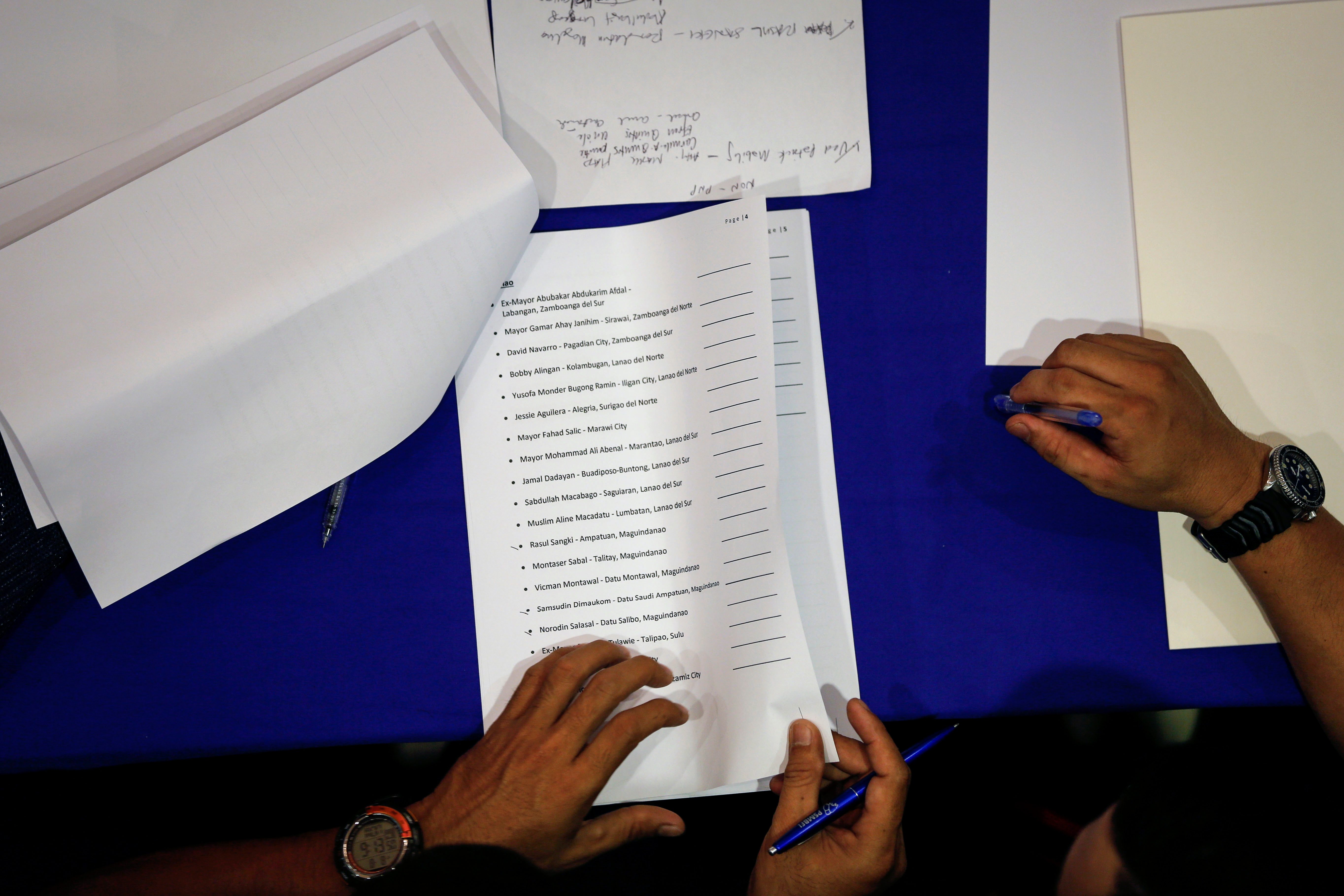 NAMES. Police officers check the list of local officials and police officers involved in the illegal drug trade, who arrived to Camp Crame to surrender on August 8, 2016. EPA/MARK R. CRISTINO 