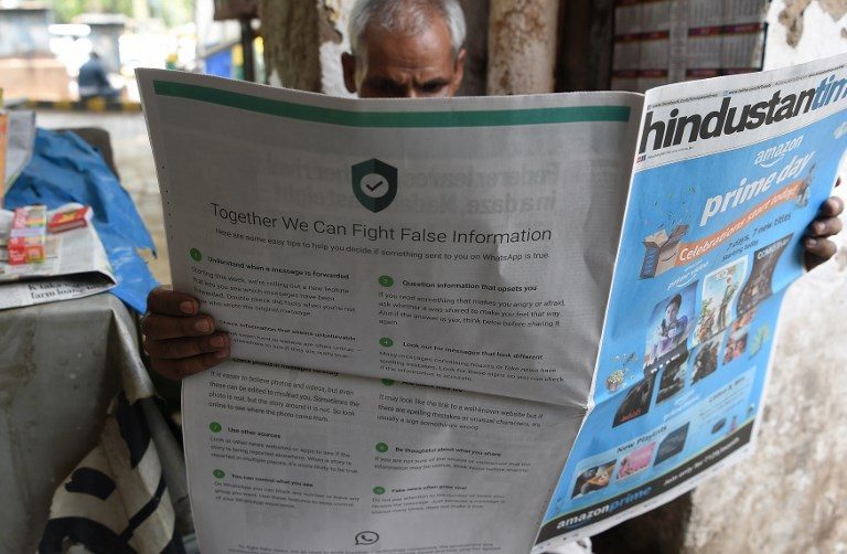 FIGHTING FAKE NEWS. This photo illustration shows an Indian newspaper vendor reading a newspaper with a full back page advertisement from WhatsApp intended to counter fake information, in New Delhi on July 10, 2018. File photo by Prakash Singh/AFP 