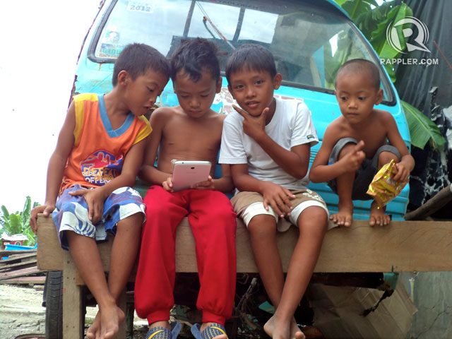 CAREFREE. Kids busy playing with a gadget in Brgy. Magallanes, Tacloban. Photo by Fritzie Rodriguez/Rappler