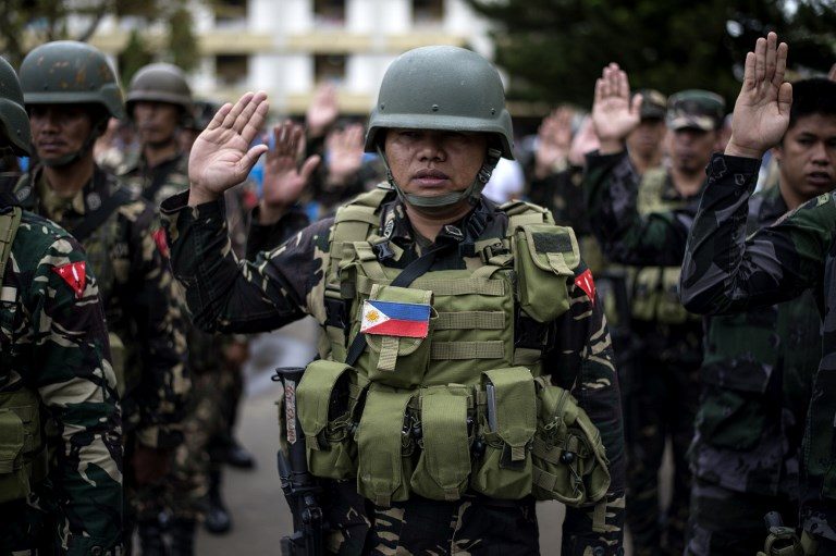 PANATANG MAKABAYAN. A soldier takes an oath during a flag-raising ceremony. Photo by Noel Celis/AFP  