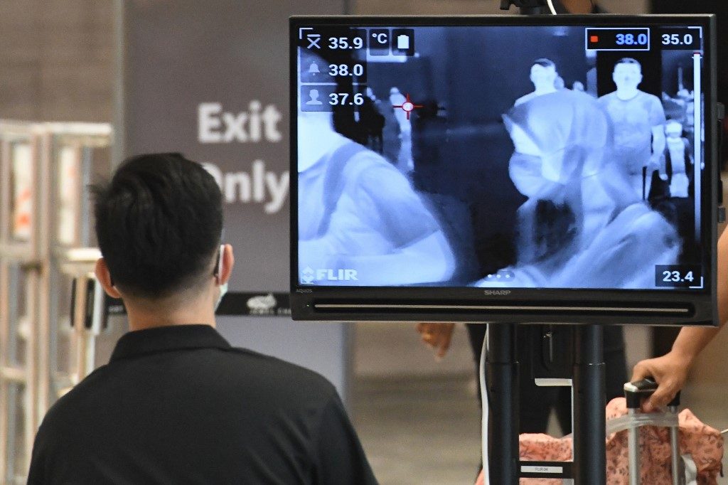 MORE CASES. A woman, wearing a protective face mask amid fears about the spread of the COVID-19 novel coronavirus, is seen on a monitor as she walks past a temperature screening check at Jewel Changi Airport in Singapore on February 27, 2020. File photo by Roslan Rahman/AFP  