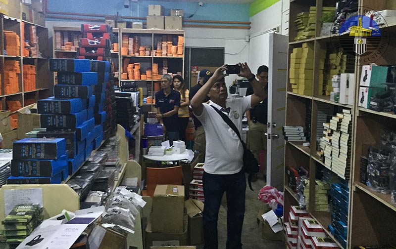 RAIDED. A man takes a photo of the gadgets found at Kim Store's storehouse in Tondo. All photos from the Bureau of Customs 