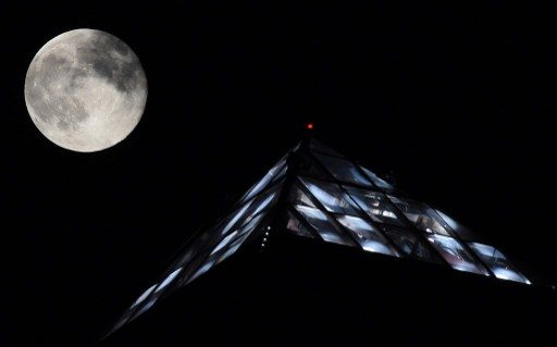 POINT OF REFERENCE. A supermoon rises behind the light on top of the Luxor Hotel and Casino on August 10, 2014 in Las Vegas, Nevada. Establish a sense of place by adding a familiar structure on the foreground. Photo by Ethan Miller/Getty Images/AFP  