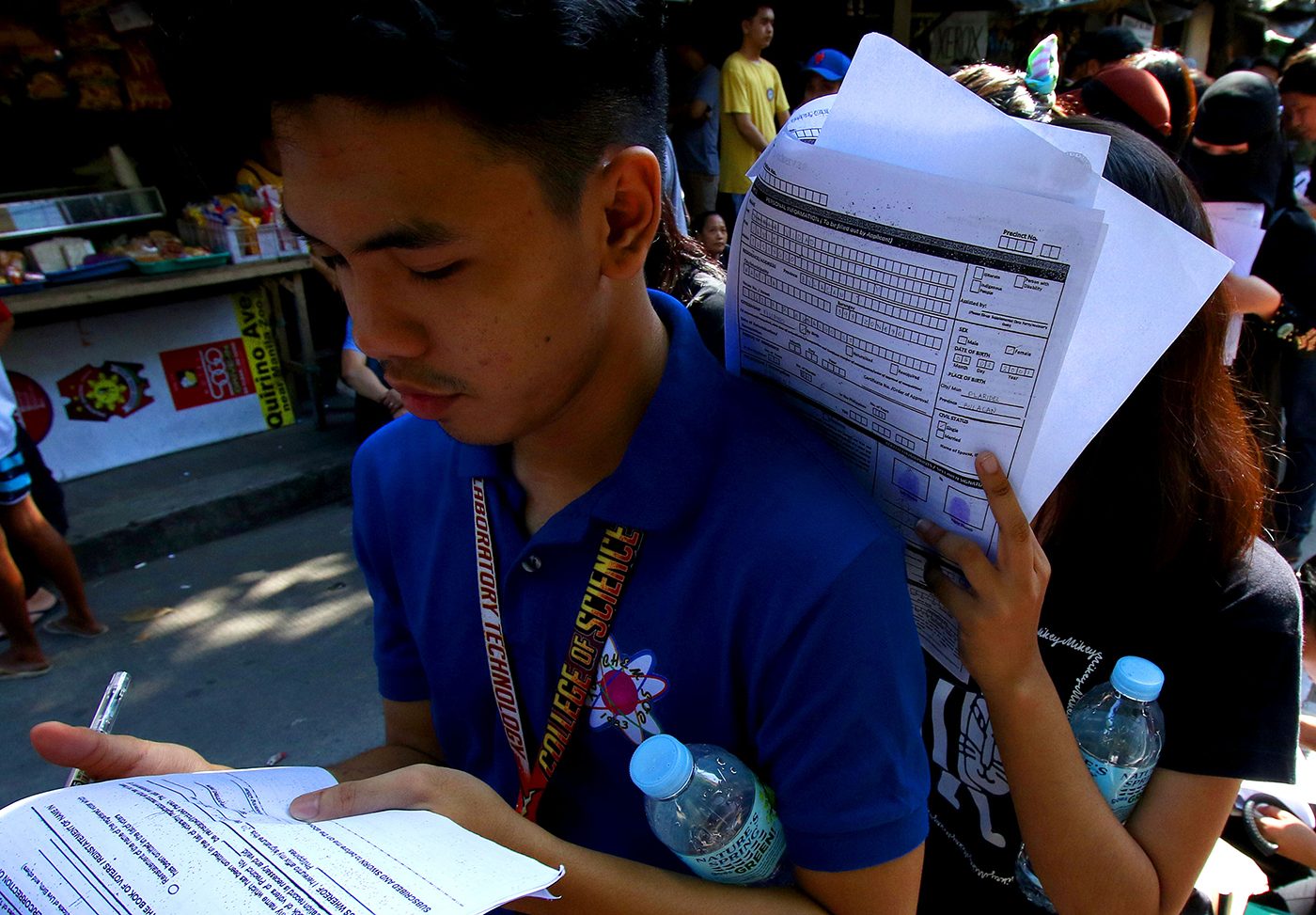 YOUTH VOTE. Students fill up their form while queued outside the Comelec office in Arroceros, Manila. Photo by Inoue Jaena/Rappler  