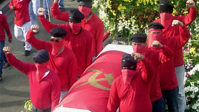 In this file photo, masked sympathizers guard the coffin bearing the remains of slain labor leader Filemon 'Popoy' Lagman, draped with the hammer and sickle flag as the funeral march heads to Marikina, February 12, 2001. Jay Directo/AFP 