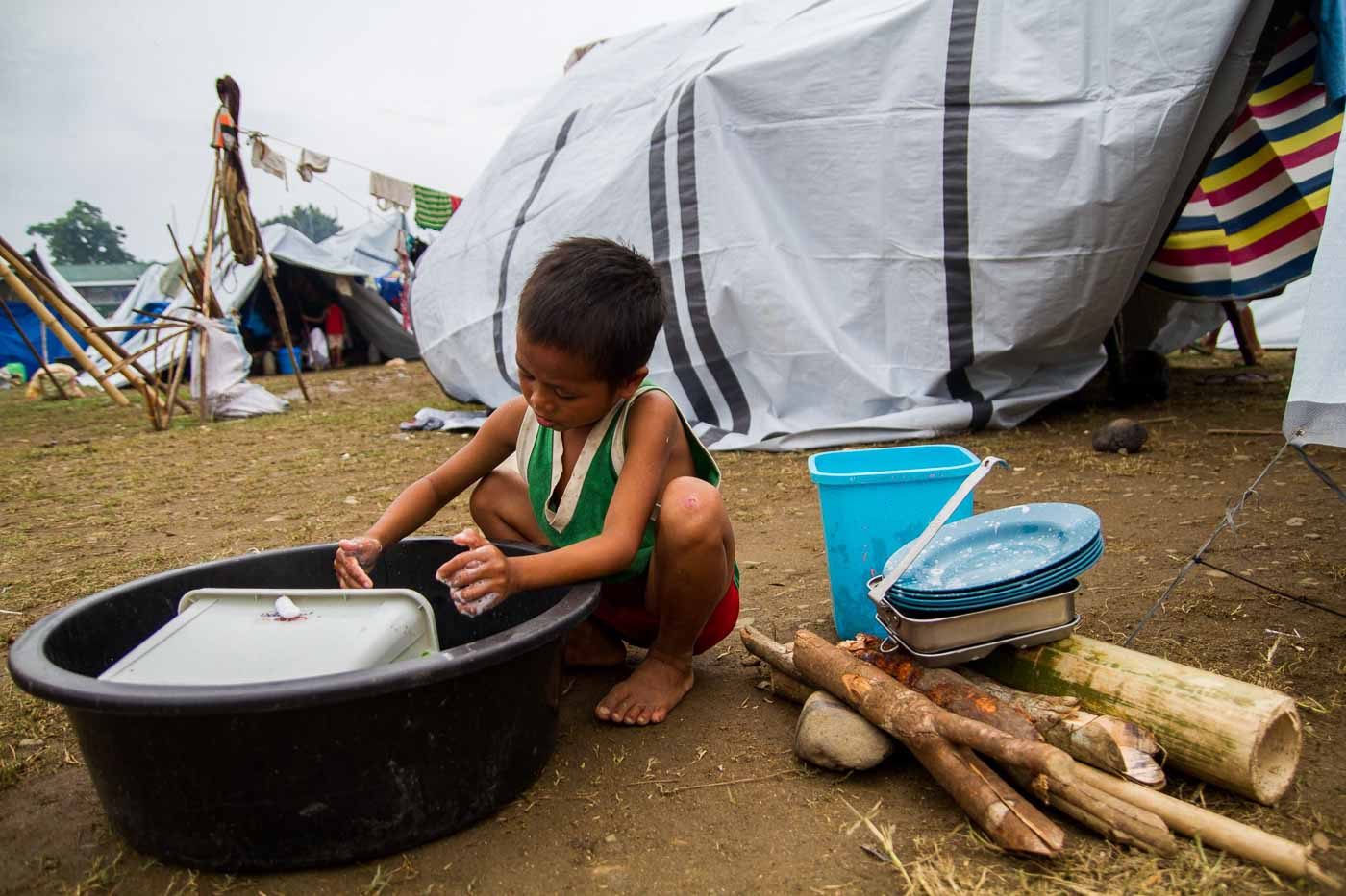 CAUGHT IN THE CROSSFIRE. A Lumad child washes dishes after the family's meal.  