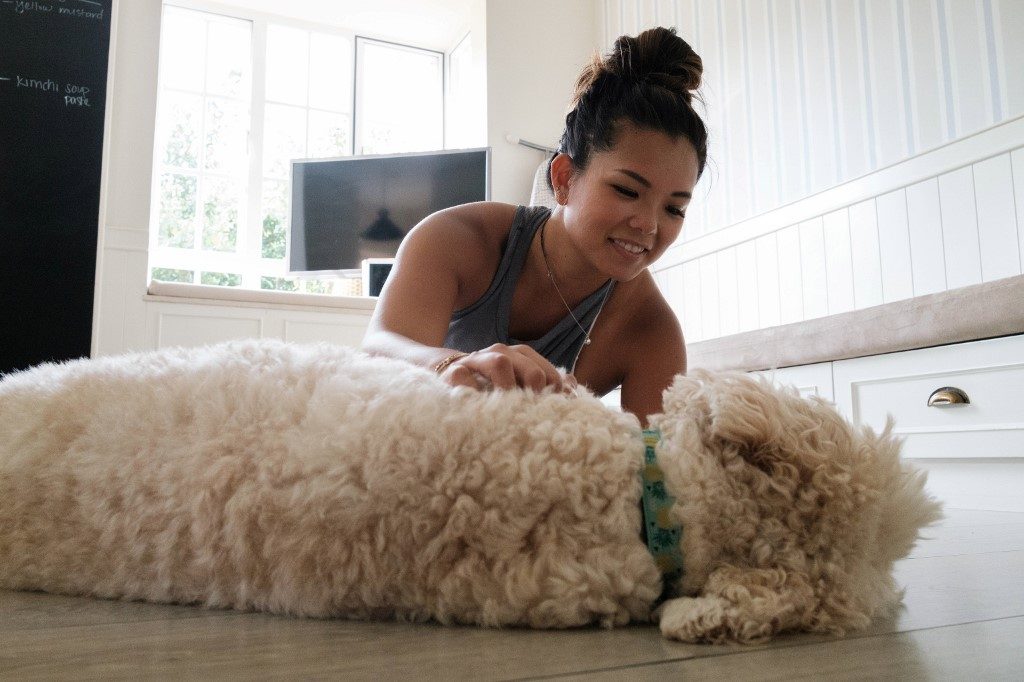 COMPANION. In this picture taken on March 26, 2020, Alison Yuen, 32, who is a Singapore national, pets her dog after taking a fitness class which was recorded by her personal trainer Kristen Handford, 33, in her kitchen in Discovery Bay, on the outlying Lantau Island in Hong Kong. Photo by Anthony Wallace/AFP 