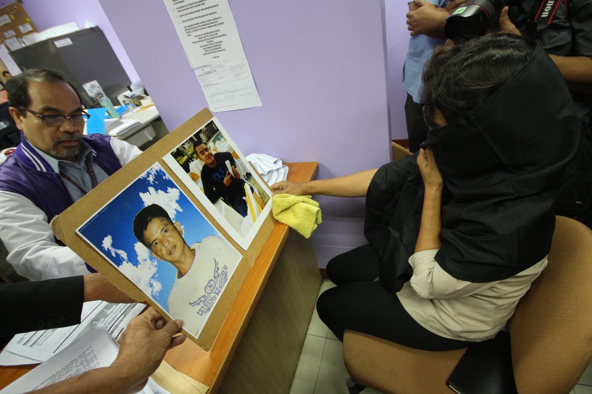 EJK? A woman shows a photo of her late husband and son, alleged victims of summary executions at the hands of police. File by Darren Langit/Rappler  