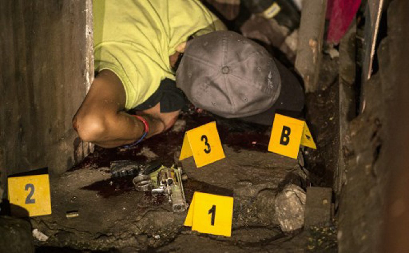 CAMPAIGN VS DRUGS. A suspected drug pusher lies dead on the ground as a police crime scene operative gathers forensic evidence after 3 suspected drug pushers were killed when a drug bust operation ended in a shootout with authorities on June 25, 2016. Photo by Noel Celis/AFP 