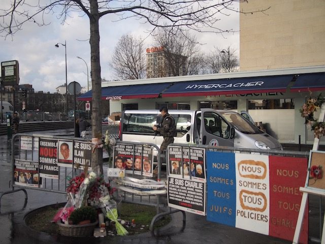 MEMORIAL. Flowers and banners at a makeshift memorial for the victims of the 2015 attack on the Jewish supermarket Hypercacher, outside Paris, France, January 6, 2016. Photo by Michaela Cabrera  