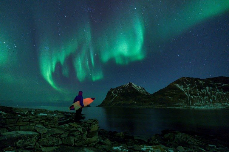 AURORA BOREALIS. A surfer looks at Northern Lights on March 10, 2018, in Utakleiv, northern Norway, Lofoten islands, within the Arctic Circle. Photo by Olivier Morin/AFP  