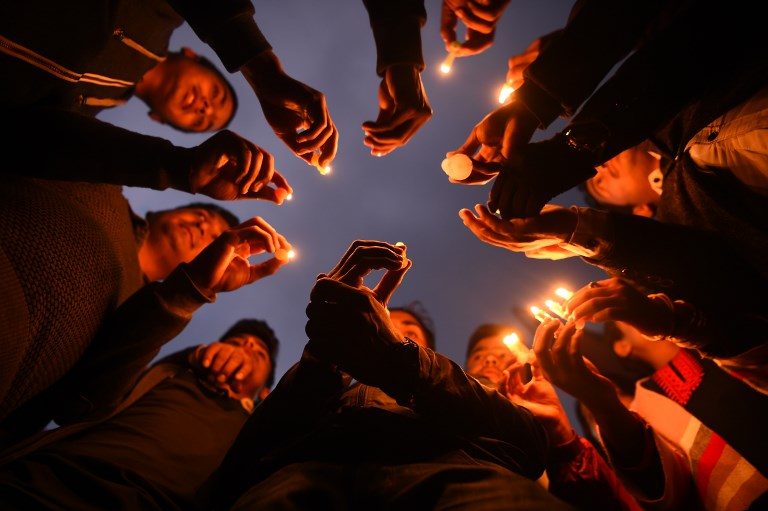 TRIBUTE. Nepali people take part in a candlelight vigil in honor of the plane crash victims in Kathmandu on March 13, 2018, a day after the deadly crash of a US-Bangla Airlines plane at the international airport. Photo by Prakash Mathema/AFP 