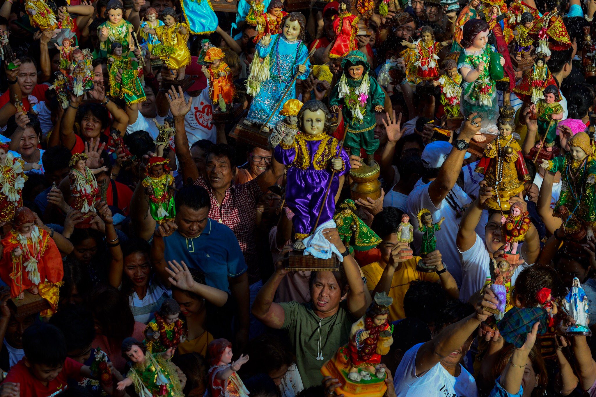 FEAST DAY. Devotees raise images of the Santo Niño (Holy Child Jesus) as they get blessed with holy water during the annual feast day of the patron Saint in Tondo, Manila, on January 20, 2019. Photo by Maria Tan/Rappler  
