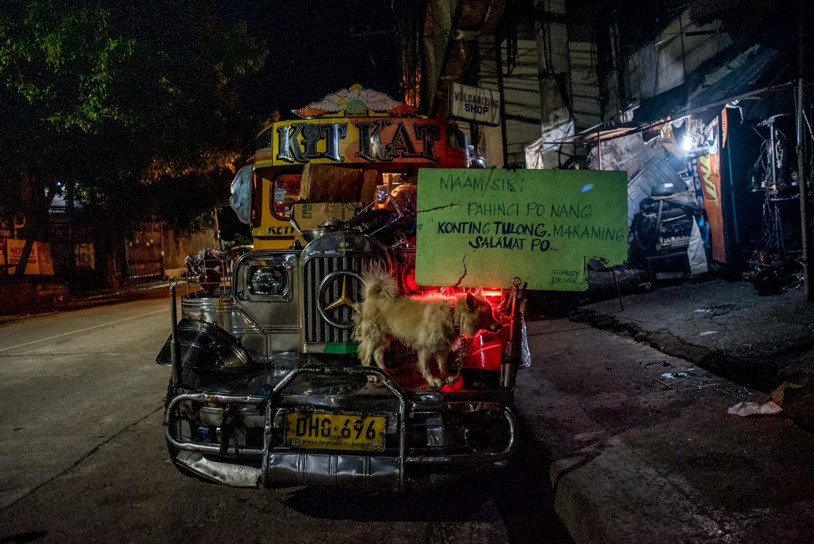 HELP. Julius parked the jeepney across his operator's vulcanizing at night. Their rescue dog, Chuchi, stays in front to guard the signage. 