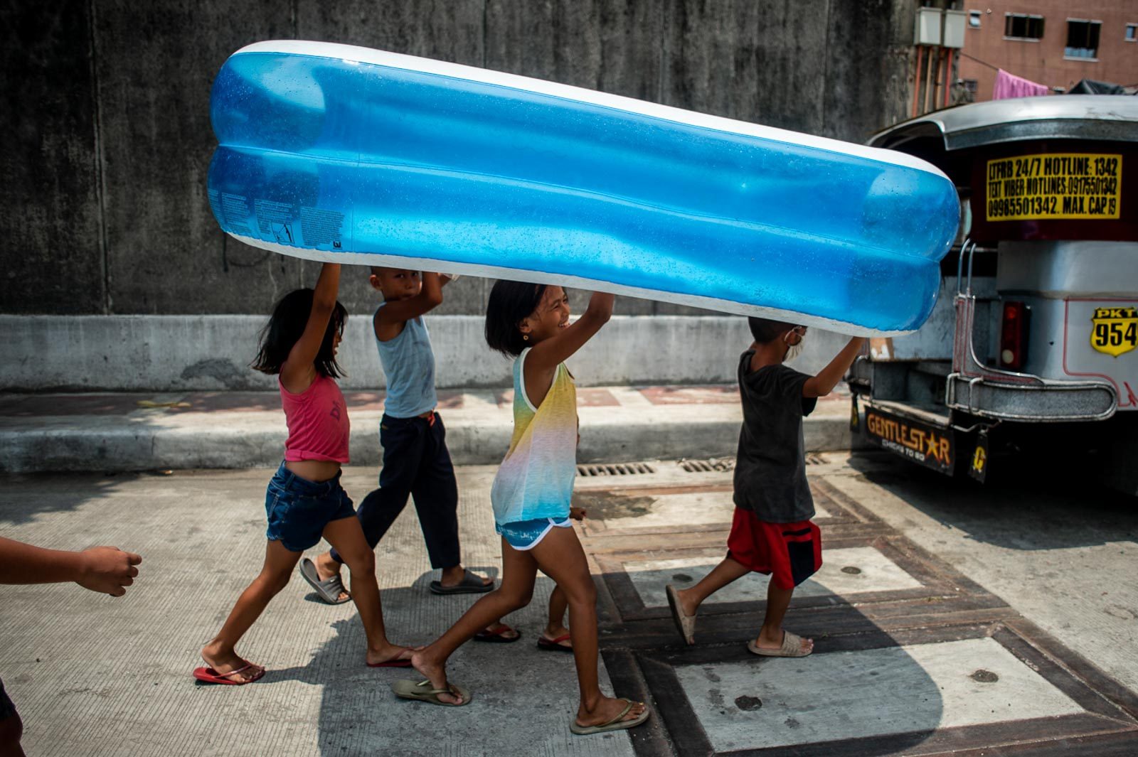 PLAYGROUND. Nicole, the eldest daughter of Julius and Erlin, lifts an inflatable pool together with her friends  – most of whom are sons and daughters of jeepney drivers too. 