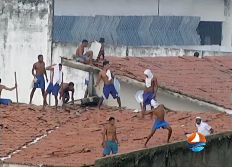 This grab from TV Ponta Negra taken on January 14, 2017 of the Alcacuz Penitentiary Center near Natal, Rio Grande do Norte state, northeastern Brazil shows inmates throwing objects from the prison roof during a riot. Ponta Negra SBT / AFP 