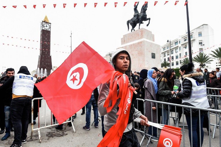 A Tunisian peddler selling national flags crosses a police roadblock on his way to a rally on January 14, 2017 in the Habib Bourguiba Avenue in the capital Tunis marking the sixth anniversary of the 2011 revolution. Fethi Belaid/AFP 
