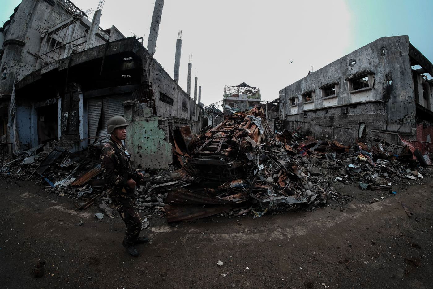 BOMBED. A soldier walks by a burned vehicle which was overturned during a bomb run. Photo by Bobby Lagsa/Rappler    