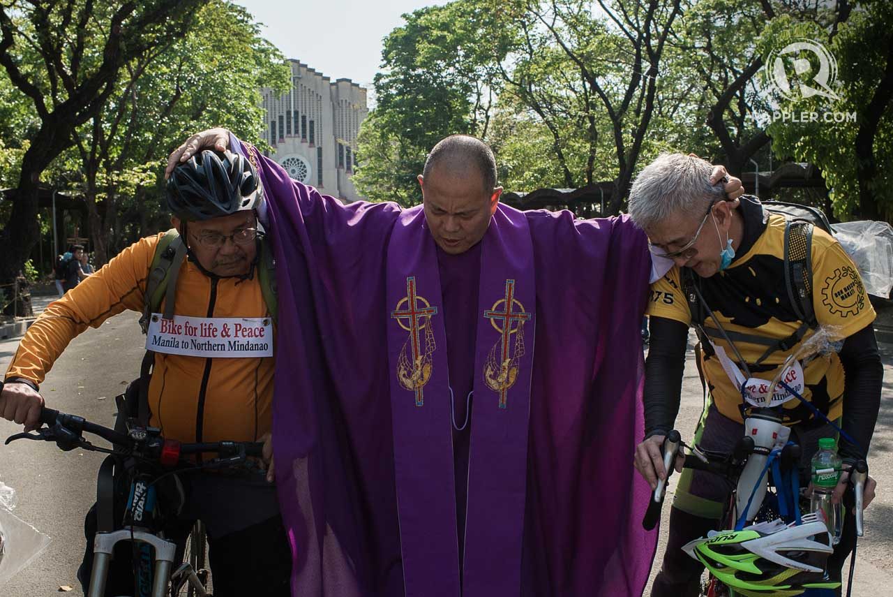 BLESSING FOR A SAFE JOURNEY. 'Running priest' Robert Reyes holds Father Picardal and lay person Chito Generoso before he sends them off to their 1500-kilometer bike trip.
Photo by Eloisa Lopez / Rappler.com   