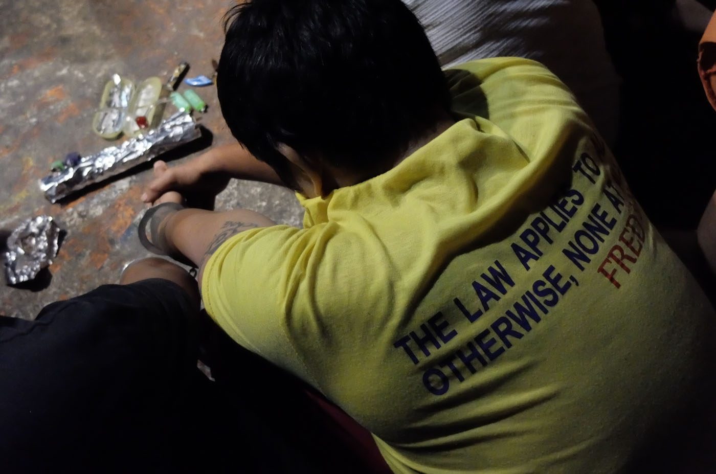 'DRUG PERSONALITY.' A drug suspect beside his alleged drug paraphernalia awaits processing by Manila police. Photo by Alecs Ongcal 