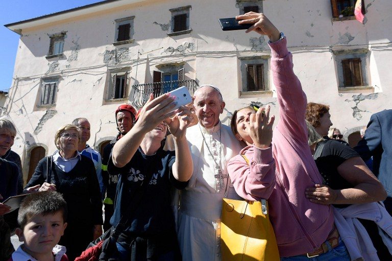 SELFIES. This handout picture taken and released by the Vatican press office on October 4, 2016 shows Pope Francis (C) posing for a picture during his visit in Accumoli, after an earthquake hit the area on August 24, a disaster that claimed nearly 300 lives. Photo by Osservatore Romano/AFP 
